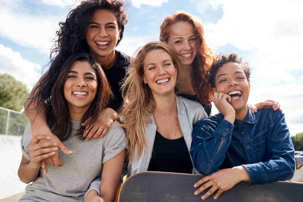 Portrait Of Female Friends With Skateboard In Urban